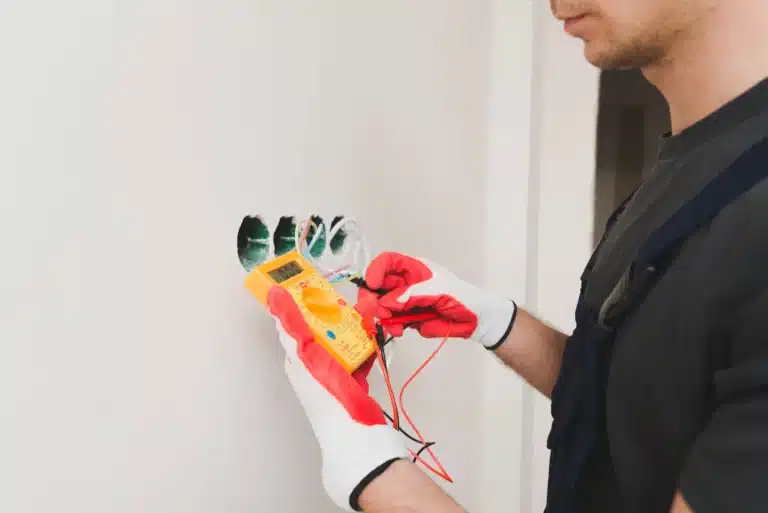 Électricien testant une prise murale à Amiens pour un contrôle de sécurité électrique.